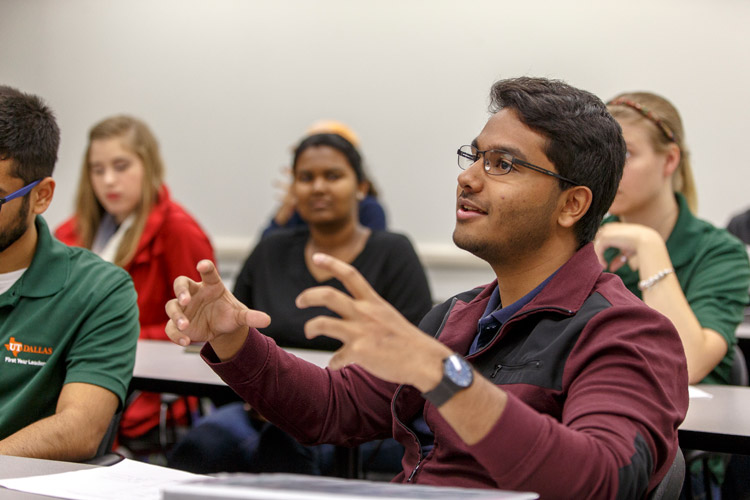 UTD student in class gestures while speaking to classmates.